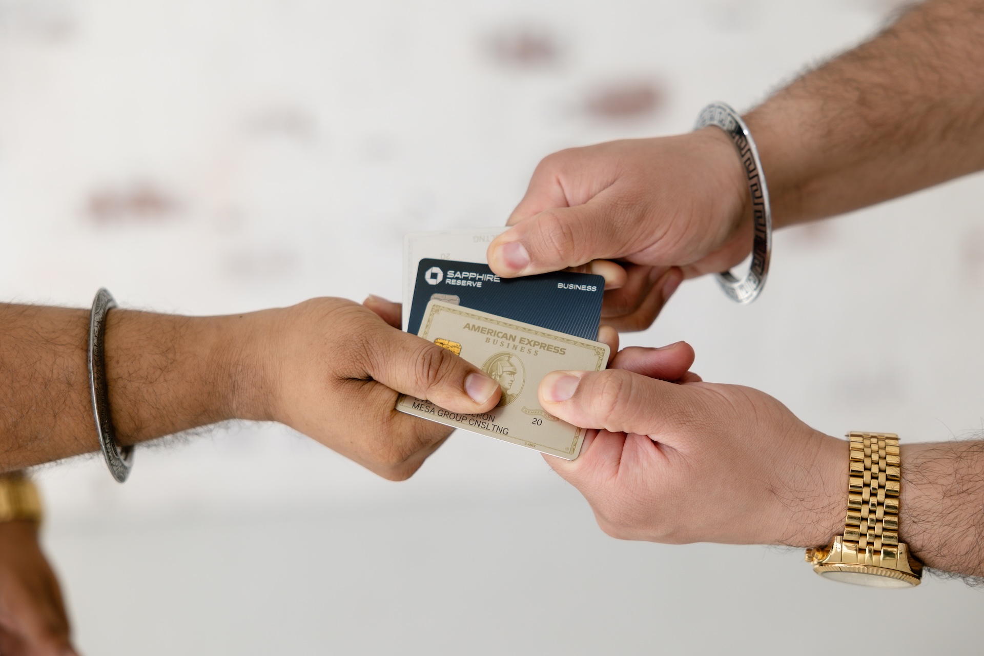 Primer plano de tarjetas de crédito empresariales American Express y Chase Sapphire Reserve sostenidas por asesores de Mesa Group Consulting