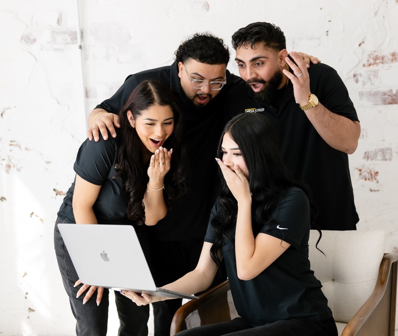 Equipo de Mesa Group Consulting reaccionando con entusiasmo a los resultados en una laptop durante una sesión de estrategia